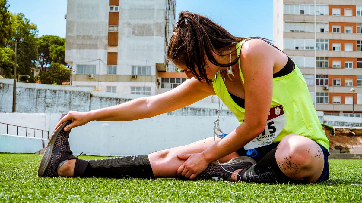 Woman stretching on grass after exercise with knee support