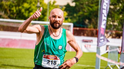 Free Male athlete celebrating victory with thumbs up after marathon race outdoors. Stock Photo