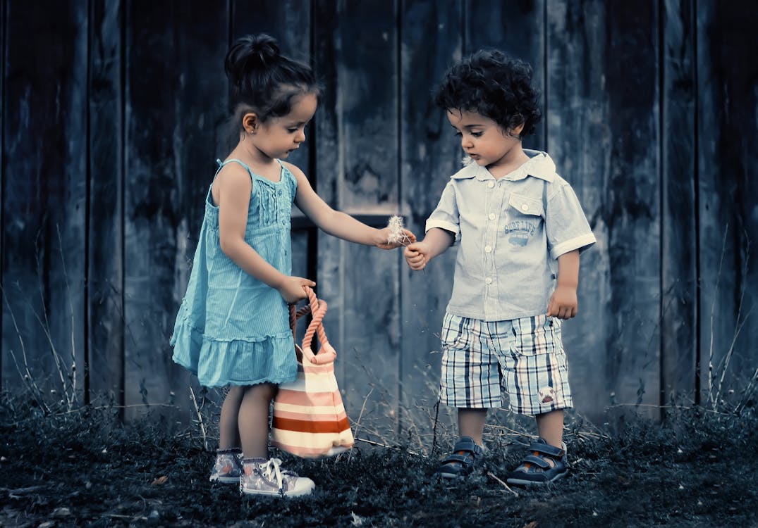 Boy and Girl Standing Near Wooden Wall