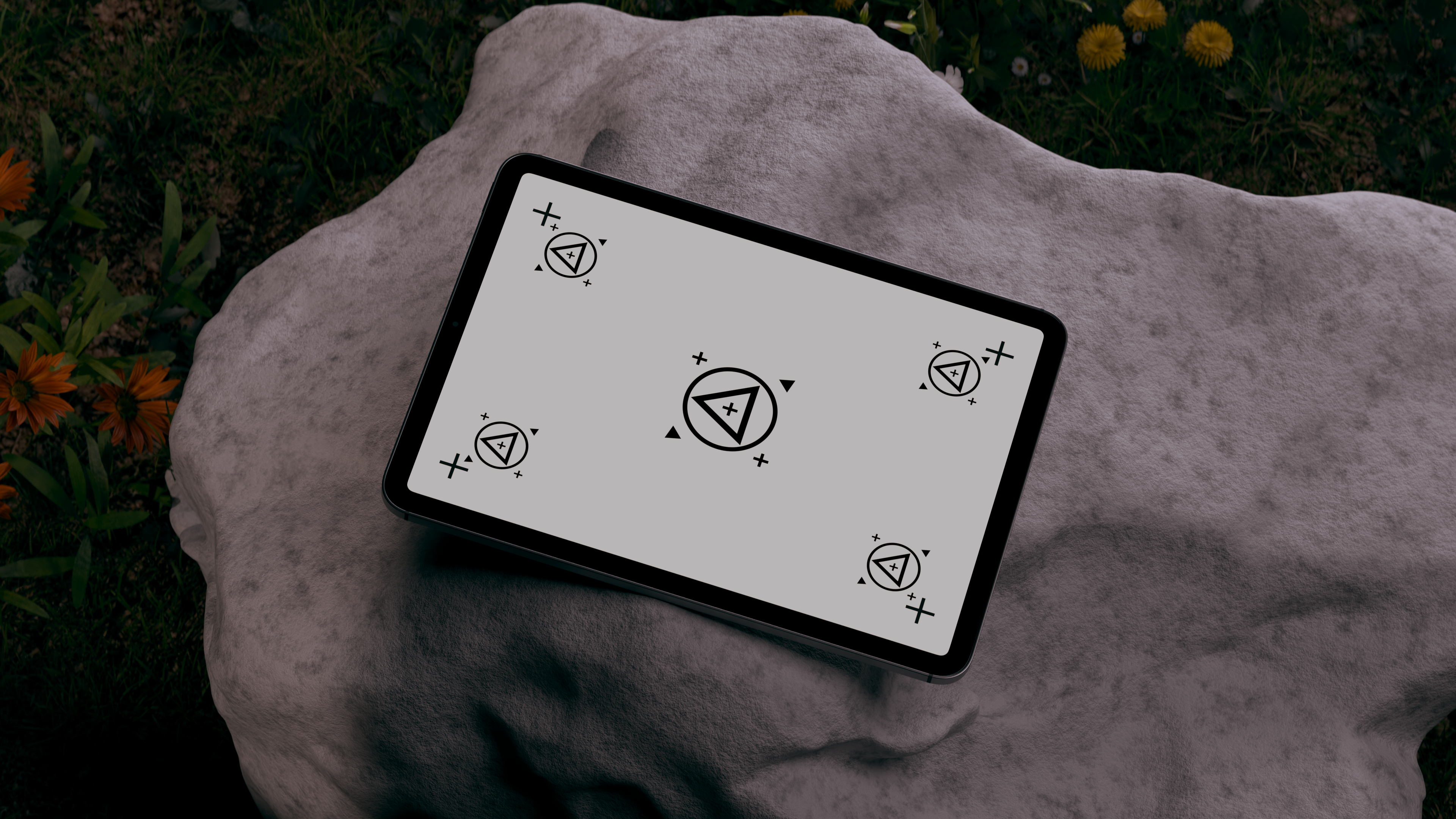 A modern tablet with an artistic design rests on a rock outdoors.