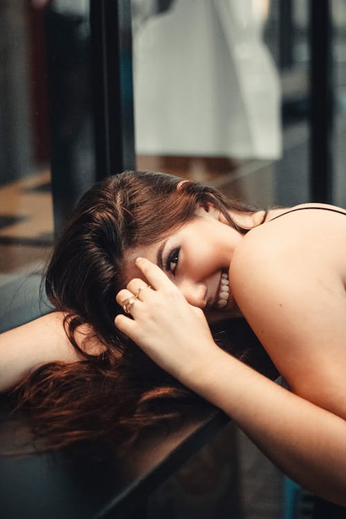 Foto De Uma Mulher Sorridente, Descansando A Mão E A Cabeça Na Mesa