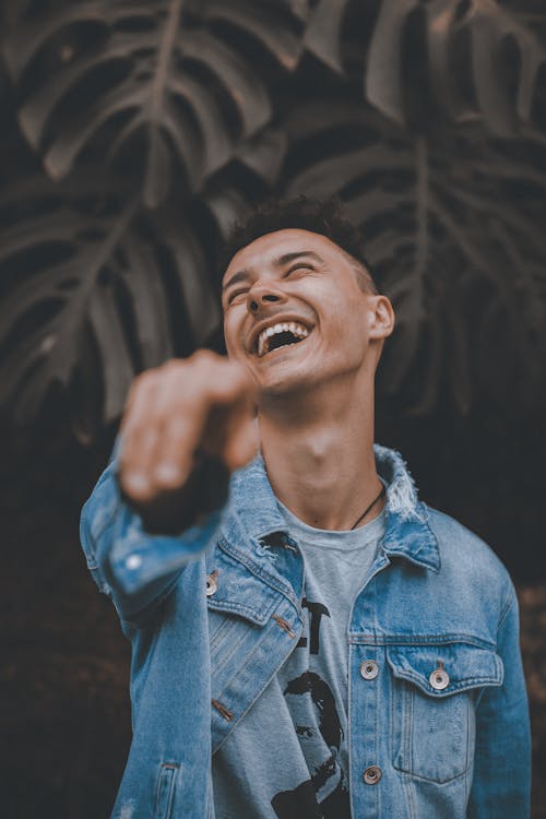 Free Selective Focus Photo of Man in Blue Denim Jacket Posing With His Head Back Laughing While Pointing Finger  Stock Photo