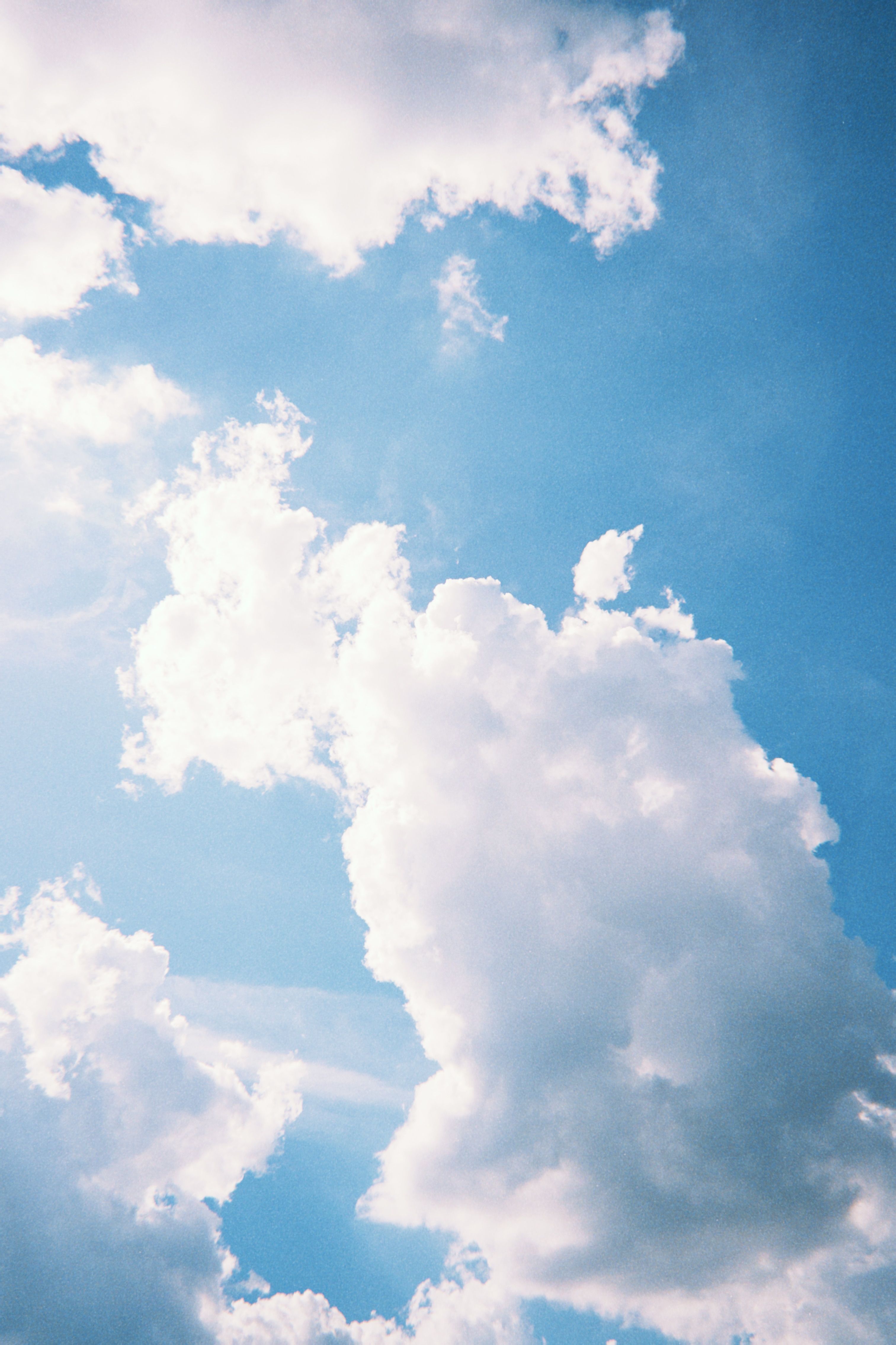 A serene image capturing fluffy white clouds floating against a clear blue sky in Poznań, Poland.
