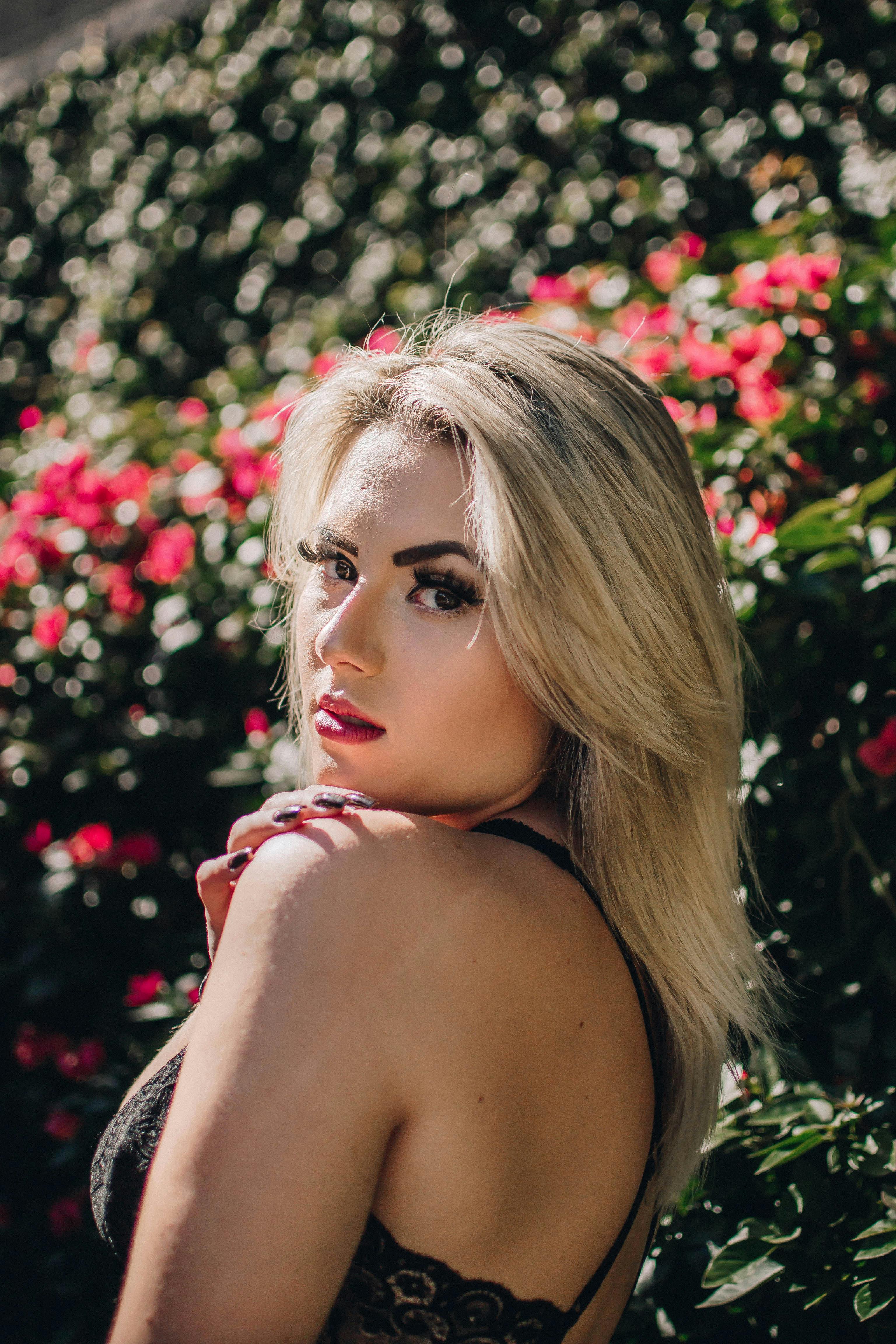 一幅金发女子的优雅肖像置于花卉背景中，突显时尚与美丽