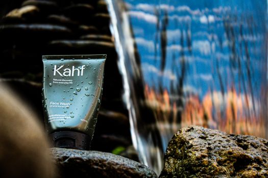 Kahf face wash displayed next to rocks and water, emphasizing natural and refreshing qualities.