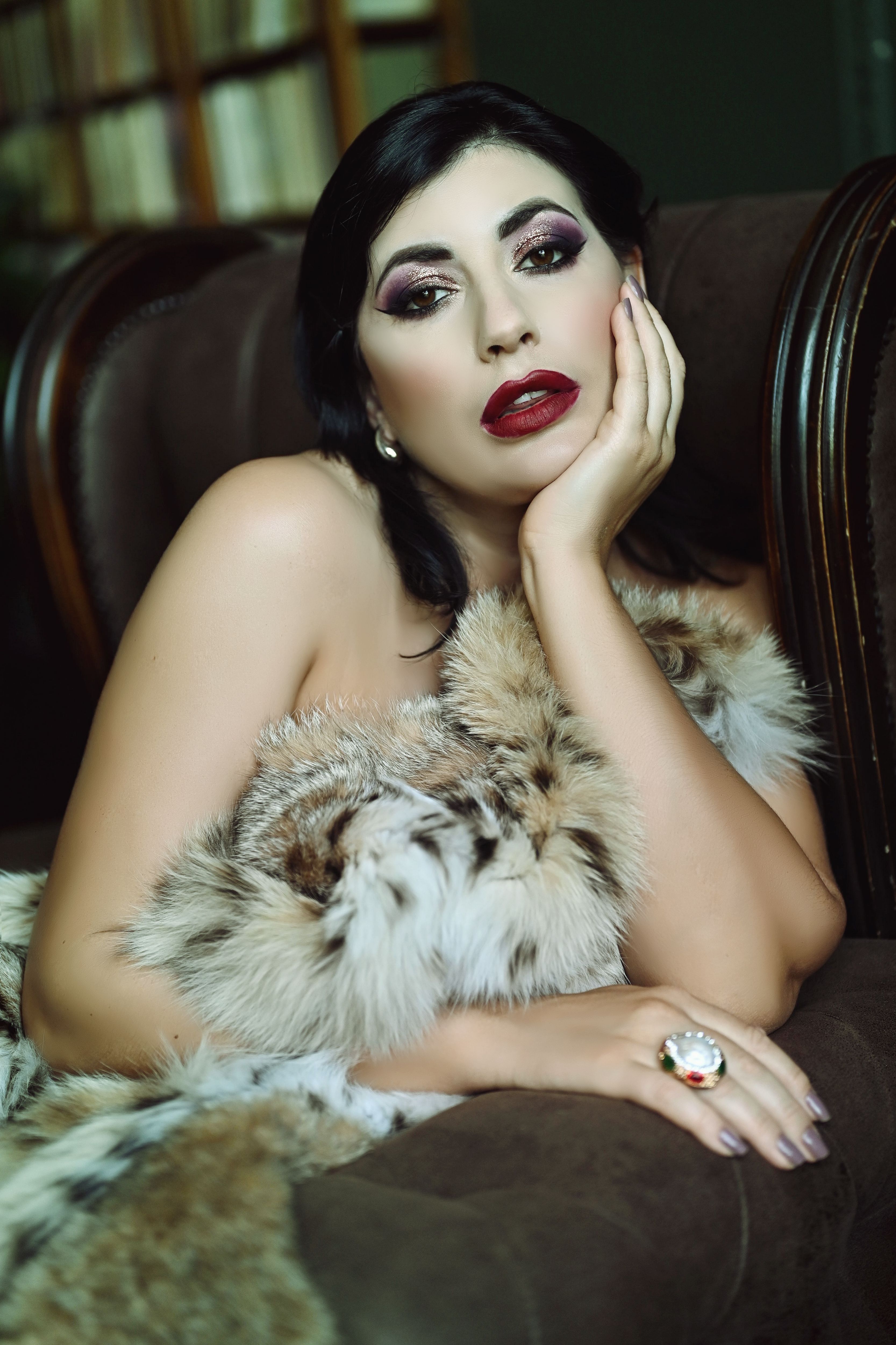 Captivating portrait of a glamorous brunette woman wrapped in fur, posing elegantly indoors.