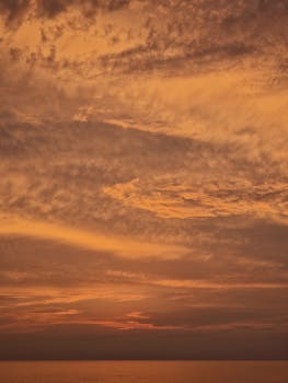 Beautiful ocean sunset with golden clouds creating a serene and warm atmosphere.