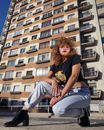 Trendy young woman in tee and jeans near apartment building