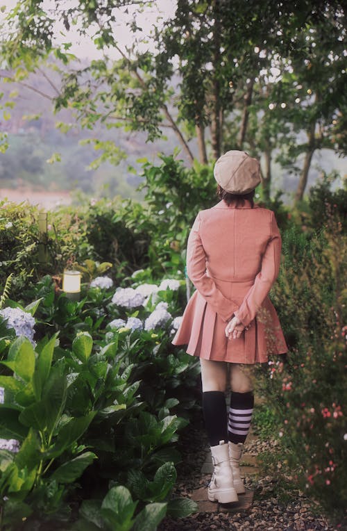 Free A girl in a pink jacket and white socks is walking through a garden Stock Photo