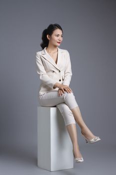 Sophisticated woman in a white suit posing elegantly in a studio setting.