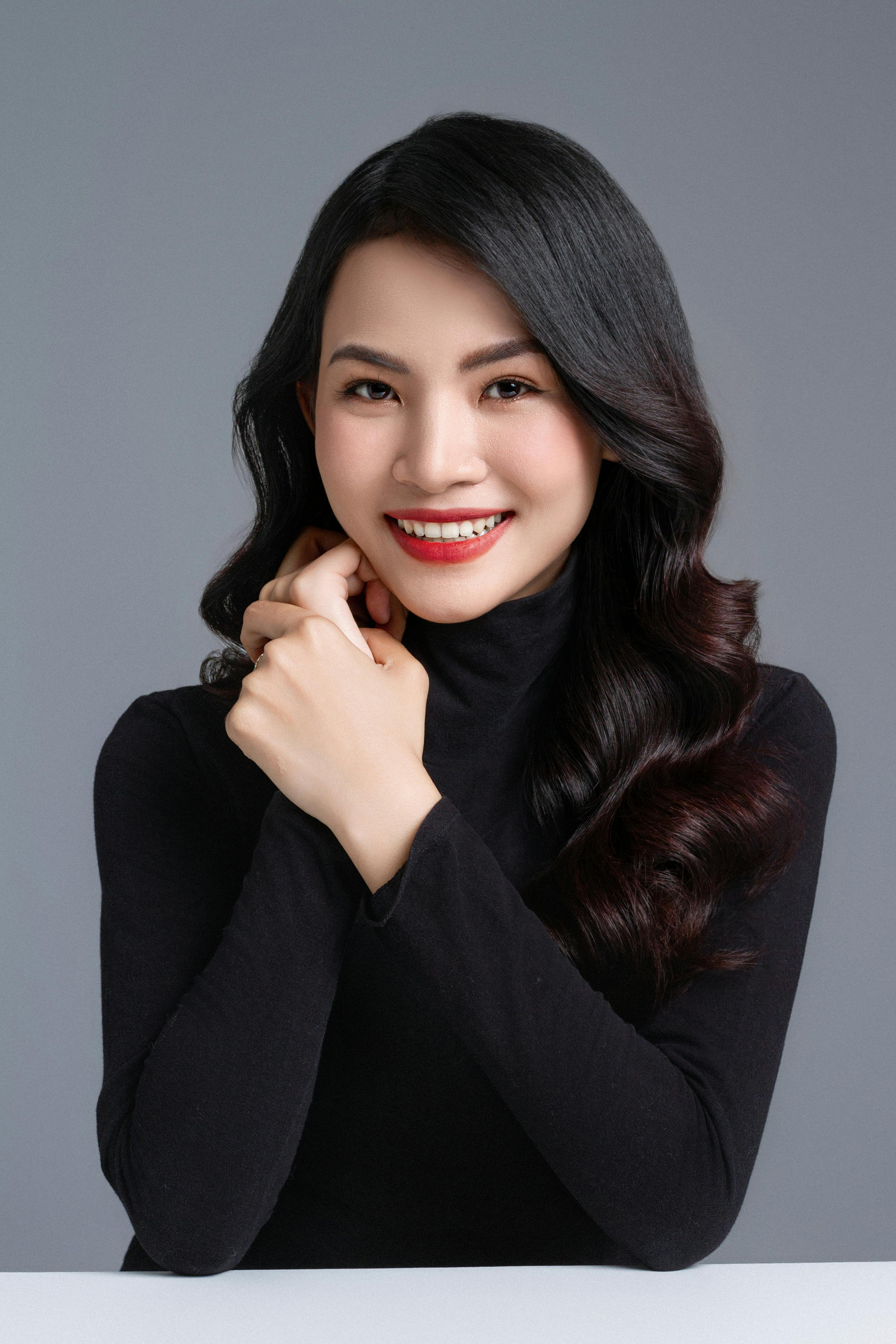 一个穿着黑色高领毛衣的微笑女人在中性背景下自信地摆姿势的工作室肖像