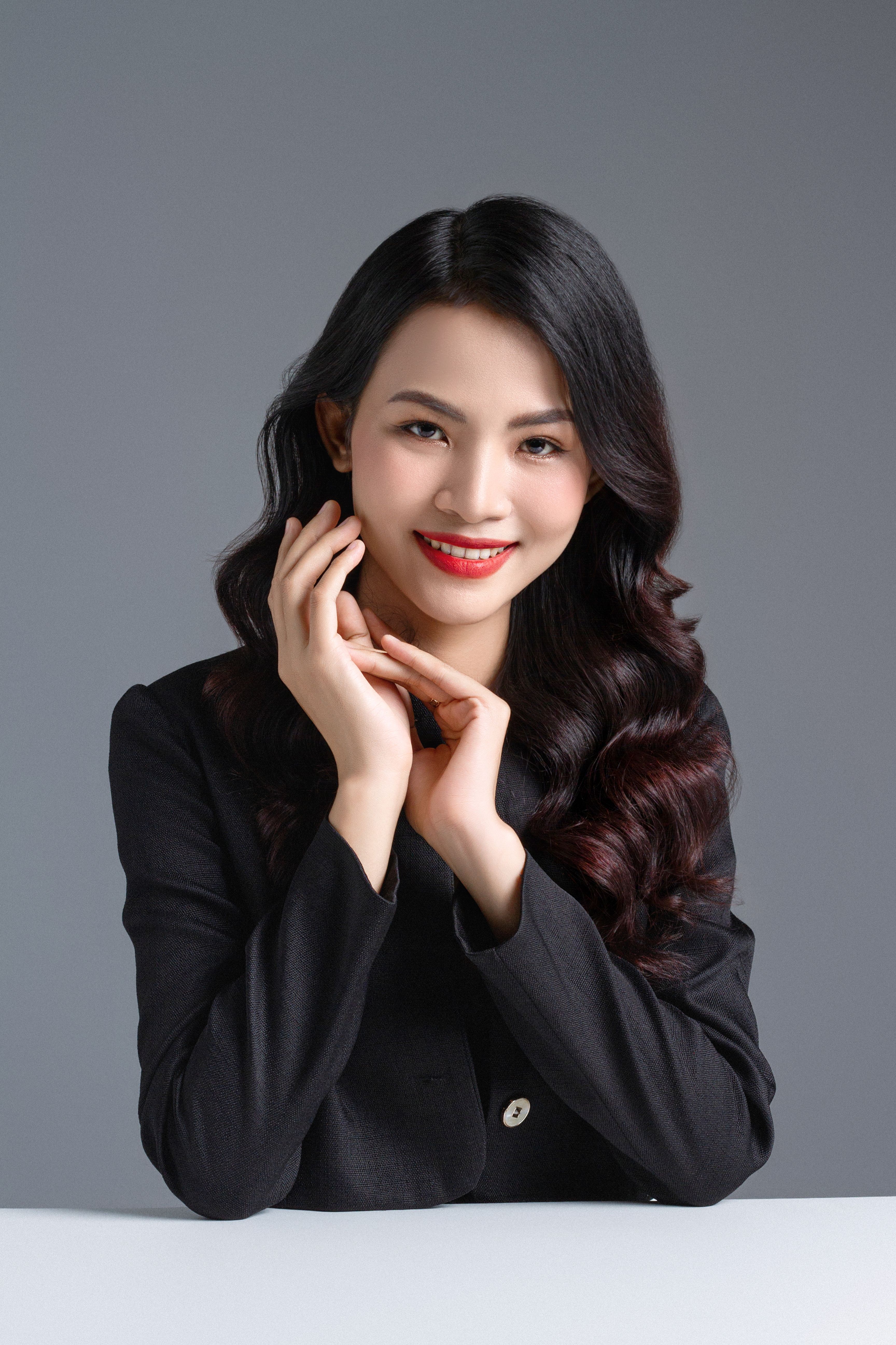 Portrait of a stylish woman in a black shirt posing confidently in a studio setting.
