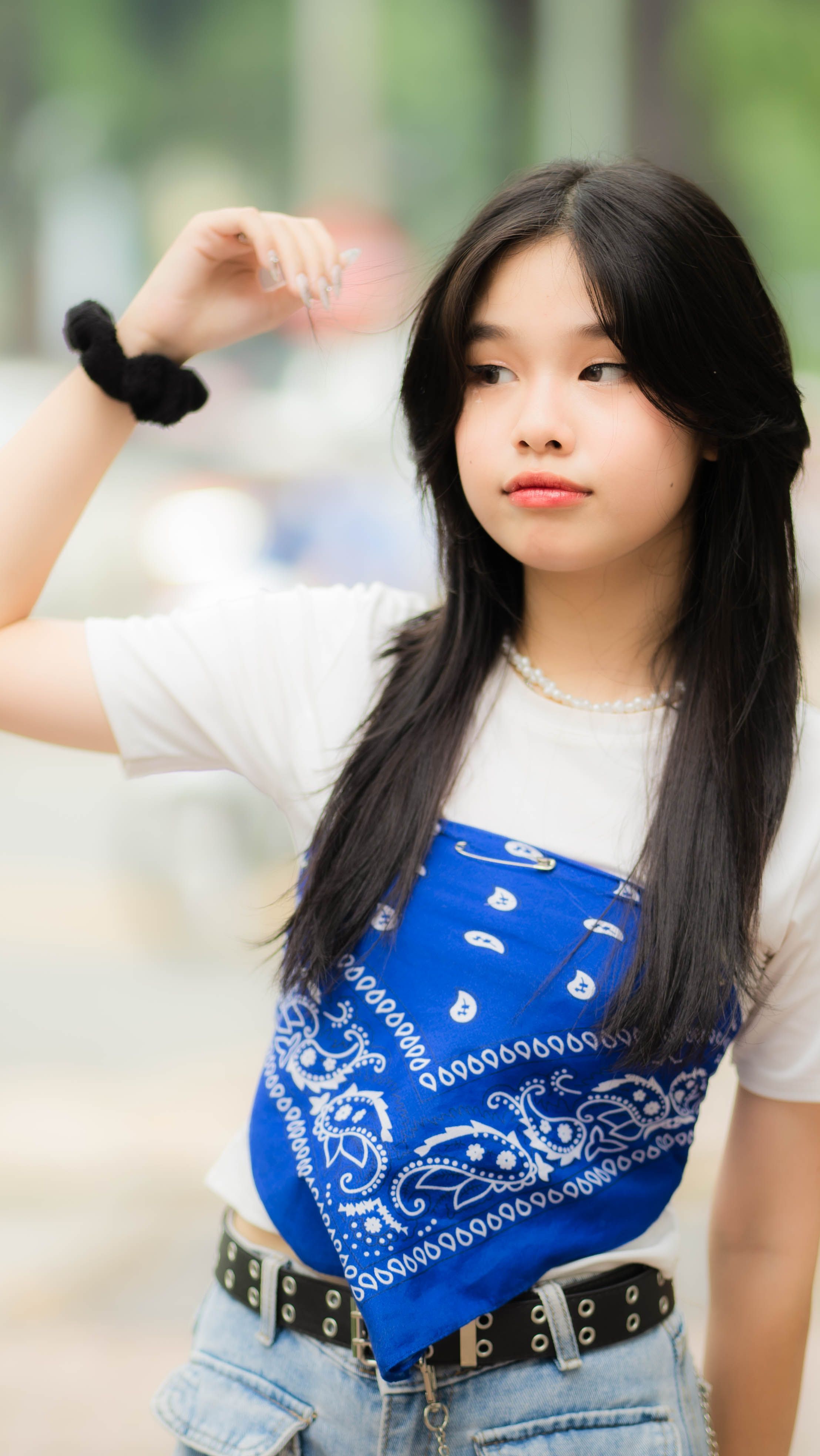 Teen girl posing outdoors with a blue bandana and casual outfit, reflecting modern fashion trends.