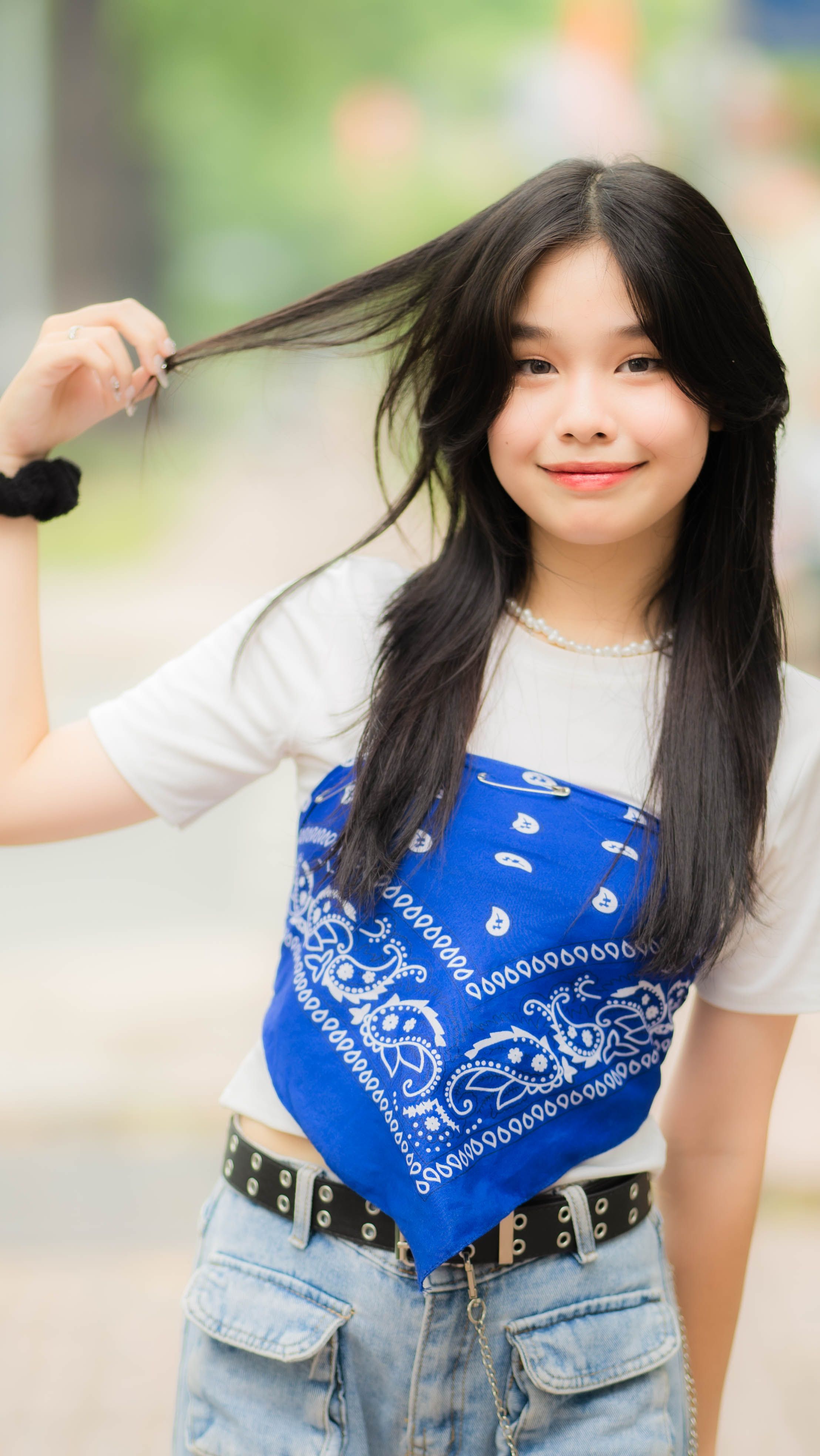 Portrait of a smiling teenager in a stylish blue headscarf top, posing outdoors.