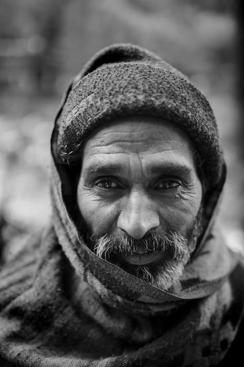 Selective Focus Grayscale Portrait Photo of Elderly Man in Beanie and Scarf Over His Head