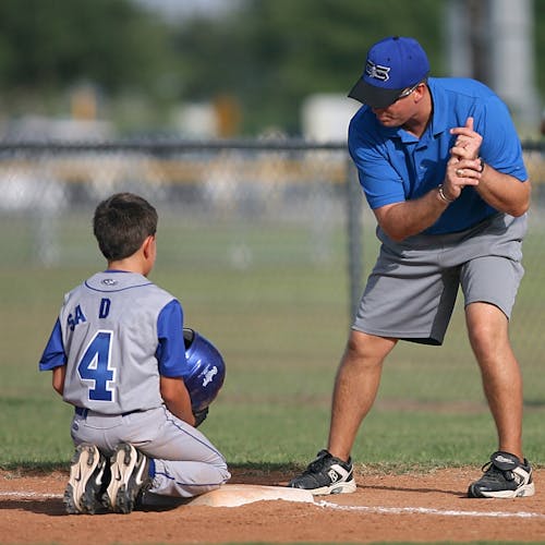 Man Kneeling on Baseball Field Beside Man