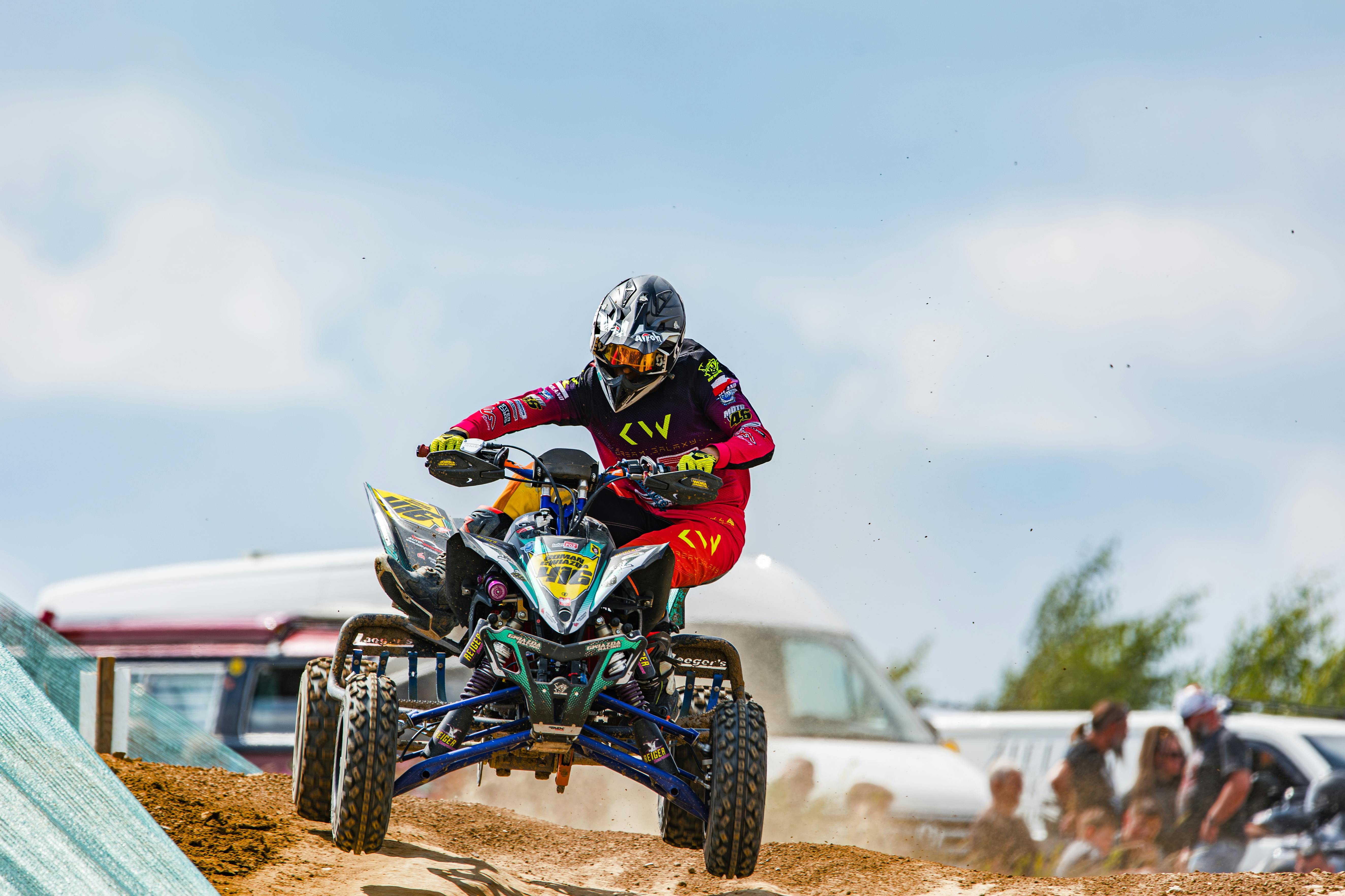 Dynamic scene of a man racing a quad bike on a sandy track.
