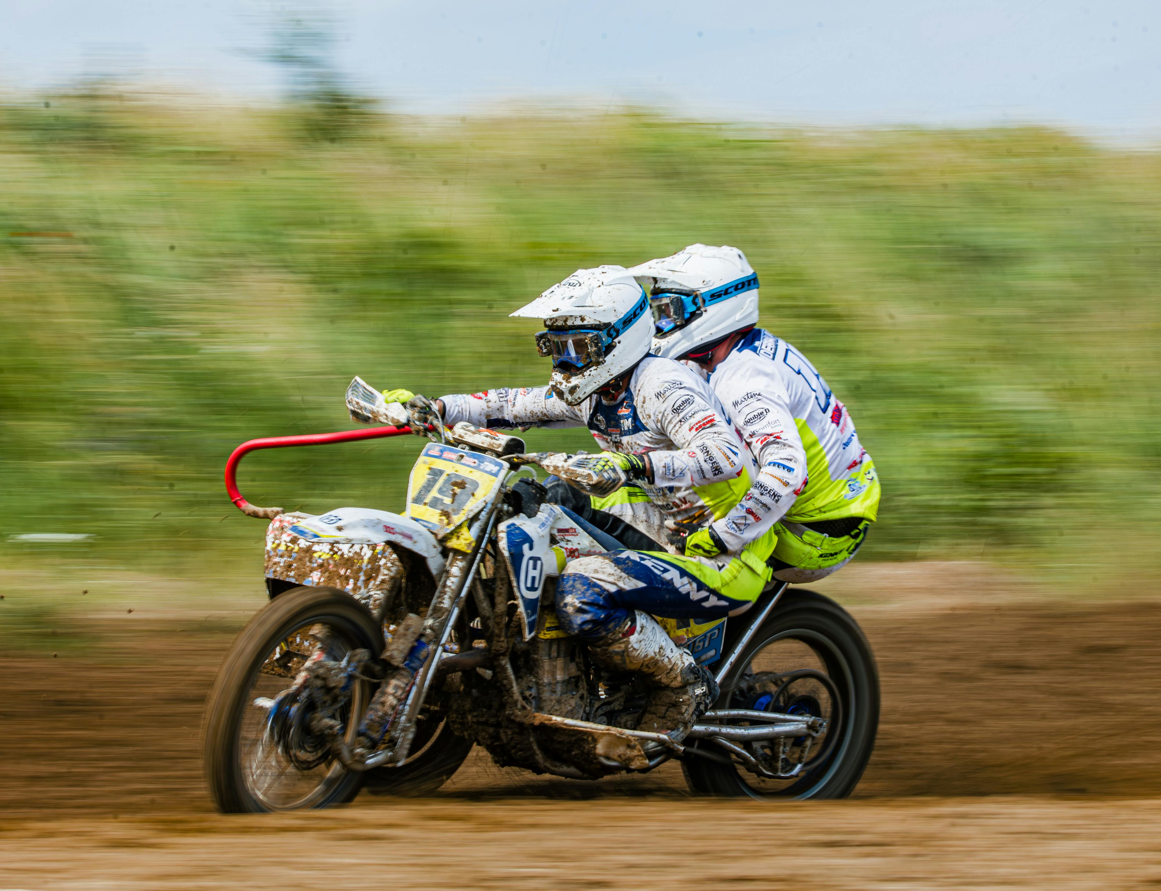 Exciting sidecar motocross race showcasing skill and speed on a dirt track.