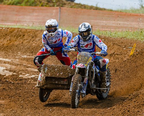 Free Exciting sidecar motocross race with riders navigating muddy track in full gear. Stock Photo