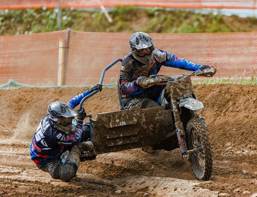 Free Dynamic sidecar motocross race with two riders tackling a muddy track, showcasing competition and skill. Stock Photo