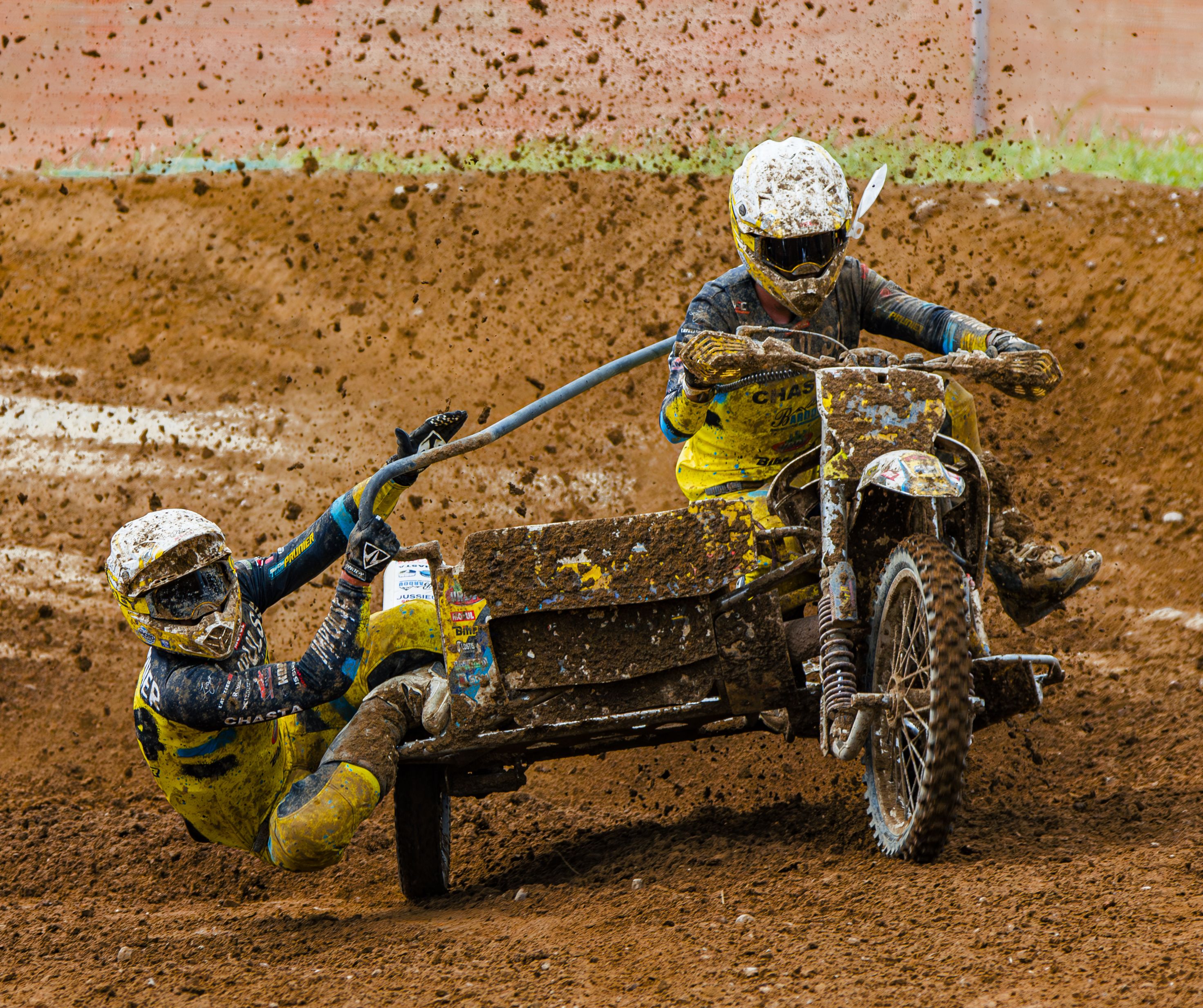 Two people riding a dirt bike on a muddy track · Free Stock Photo