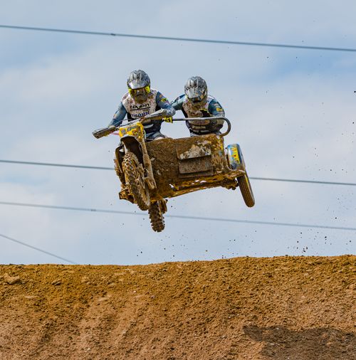 Free Dynamic image capturing a sidecar motocross team jumping over dirt track during a race. Stock Photo