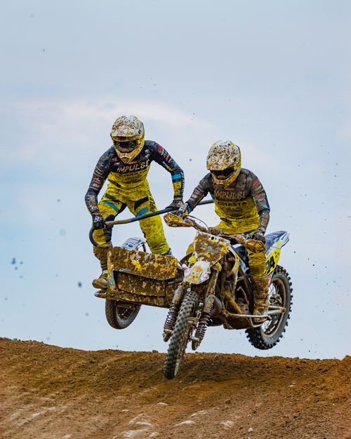 Free Thrilling sidecar motocross racers catch air on a dirt track, showcasing dynamic sport action. Stock Photo