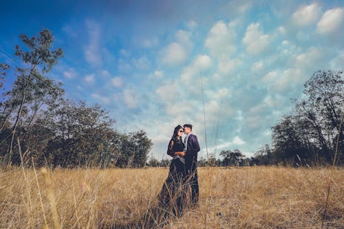 免費 互相抱著的夫婦的照片站立在棕色草地上 圖庫相片