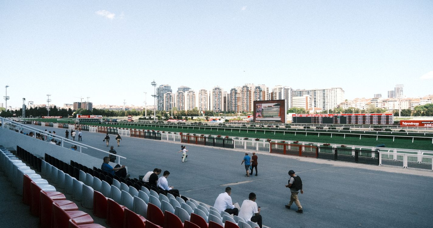 Piste d'hippodrome avec des spectateurs disséminés dans les tribunes par une journée ensoleillée