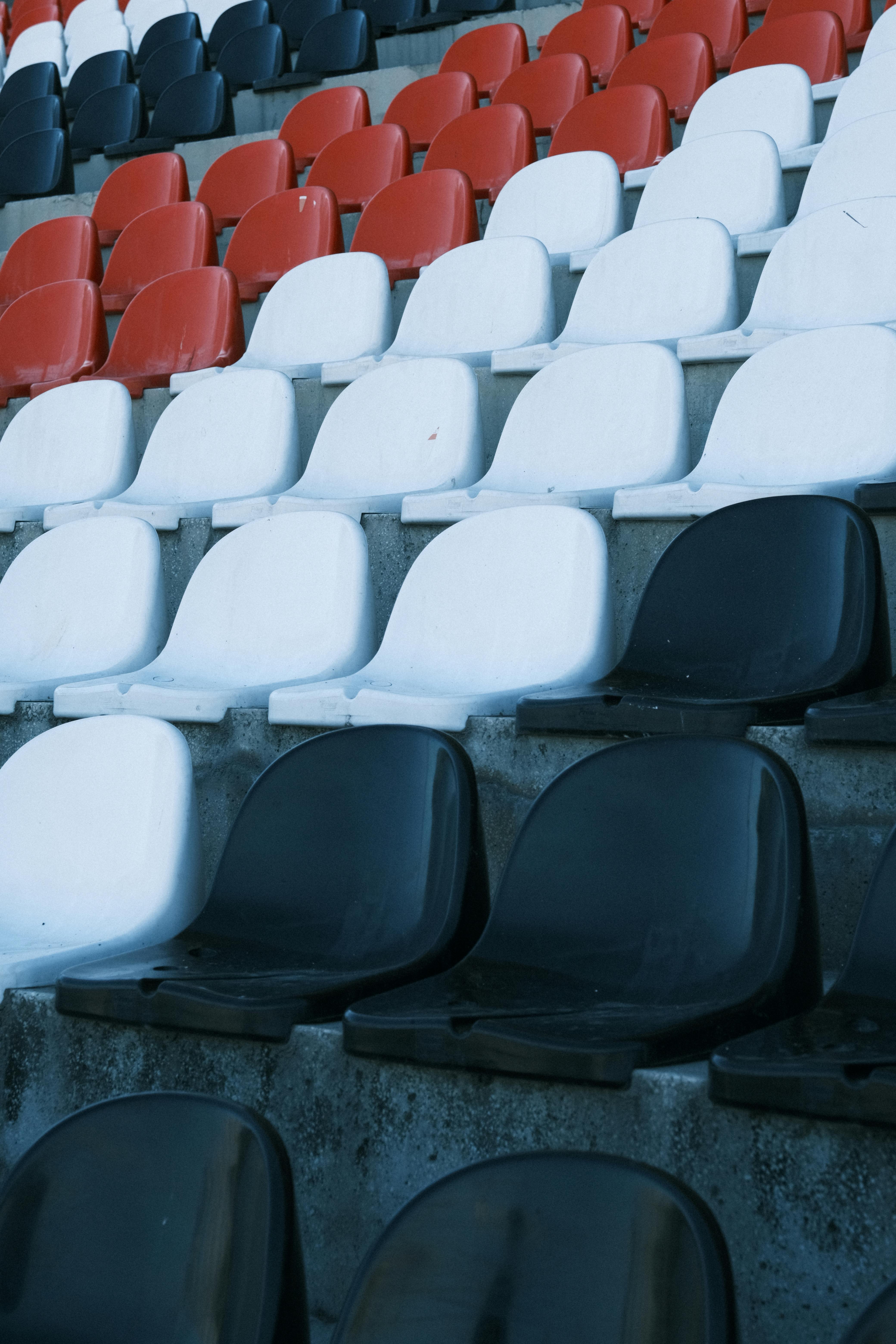 An artistic shot of red, white, and black seats in an empty sports stadium.