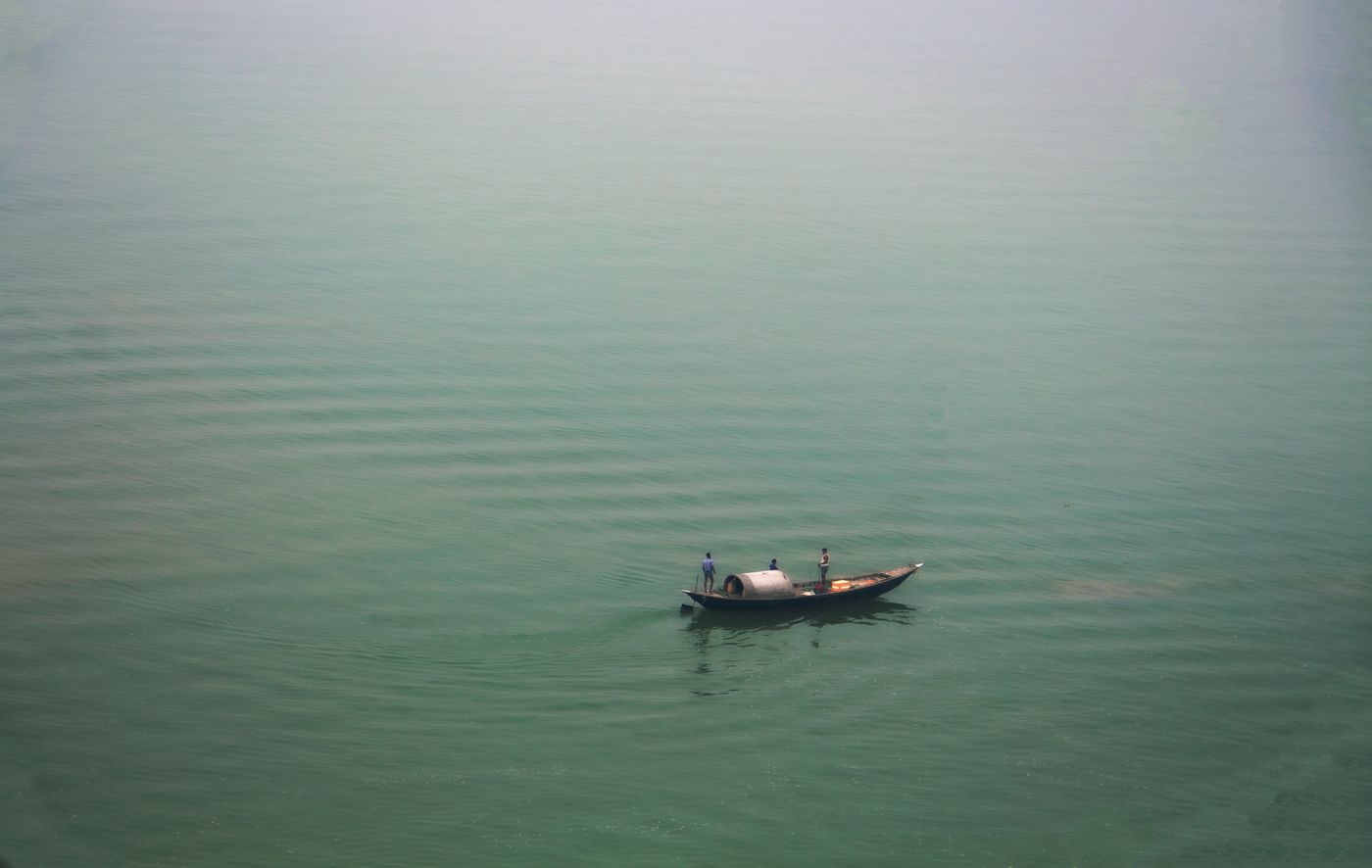 Fisherman on a wooden boat on misty water in Bangladesh
