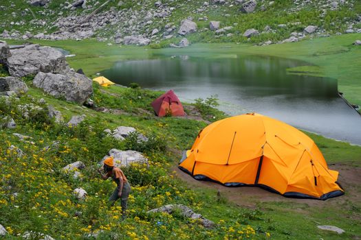 Vibrant orange tents set up by a serene mountain lake, ideal for camping and adventure.