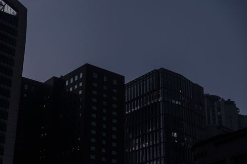 Free A cityscape featuring silhouetted skyscrapers against a darkening evening sky. Stock Photo