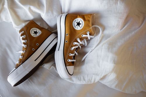Free Close-up of brown high-top sneakers on a white fabric background, showcasing casual footwear fashion. Stock Photo