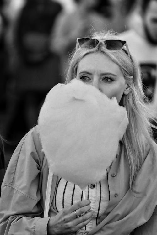 A woman is blowing a cotton candy