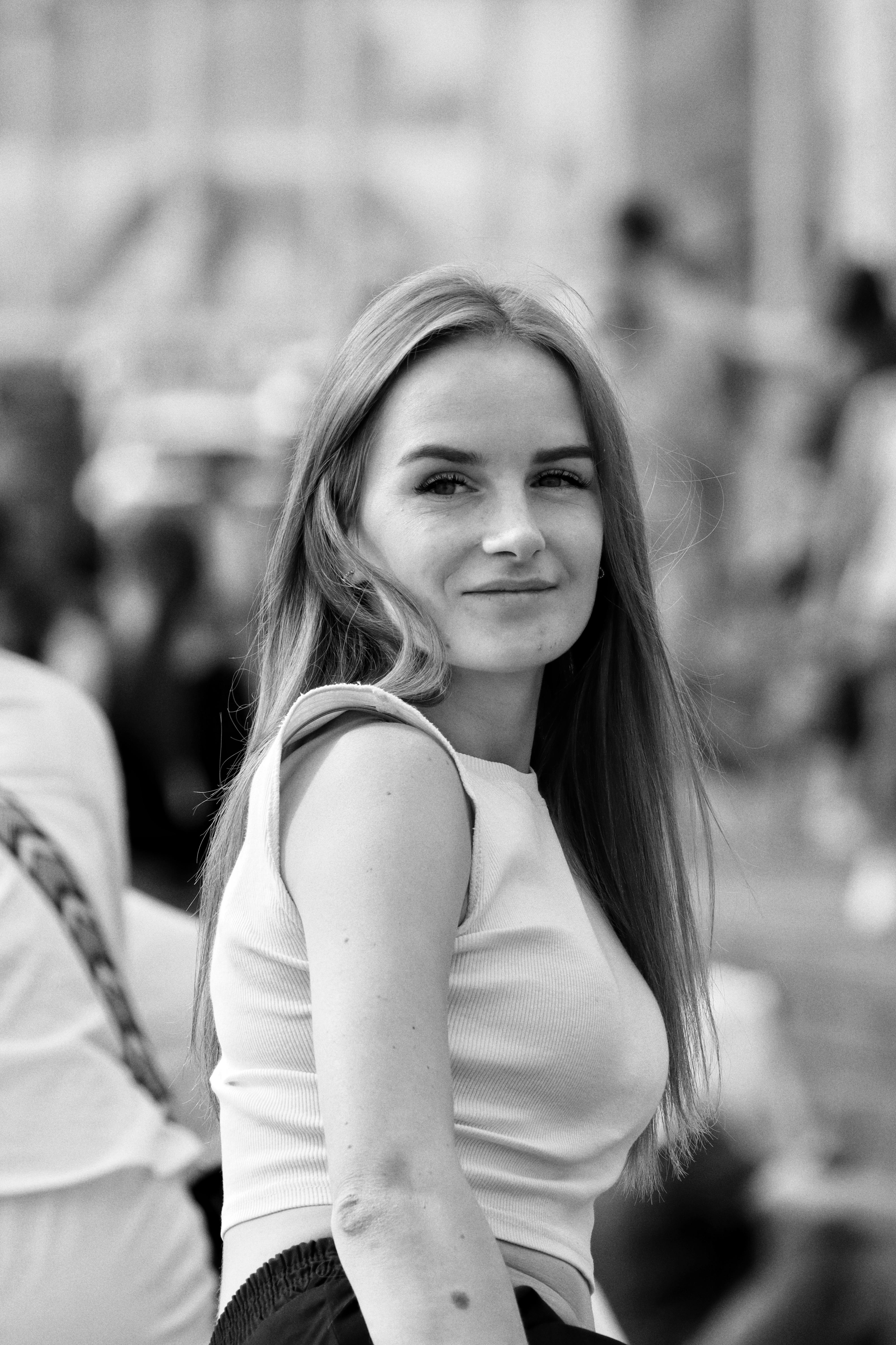Black and white portrait of smiling woman in urban environment.