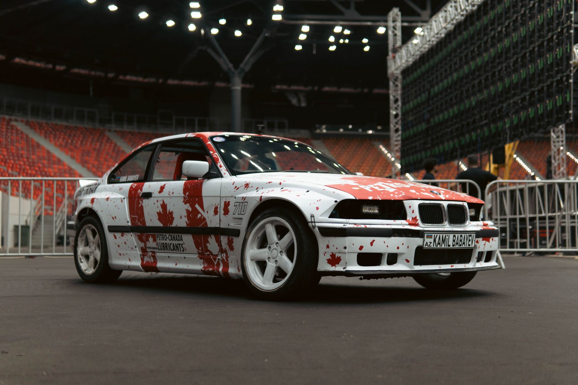 A customized car with vibrant paint designs set in a stadium. Ideal for auto enthusiasts.
