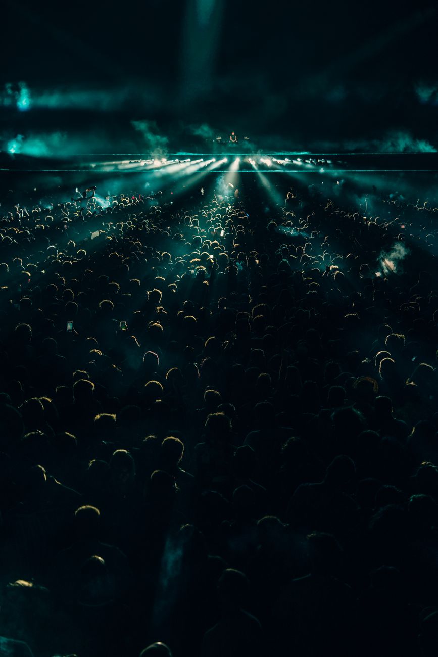 Night concert crowd under sweeping lights and haze