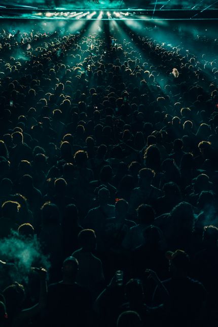 Crowd under teal stage light — photo by Noland Live on Pexels