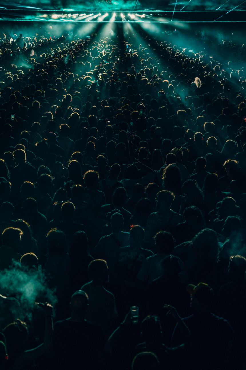 Crowd at a night concert lit by stage beams — photo by Noland Live on Pexels