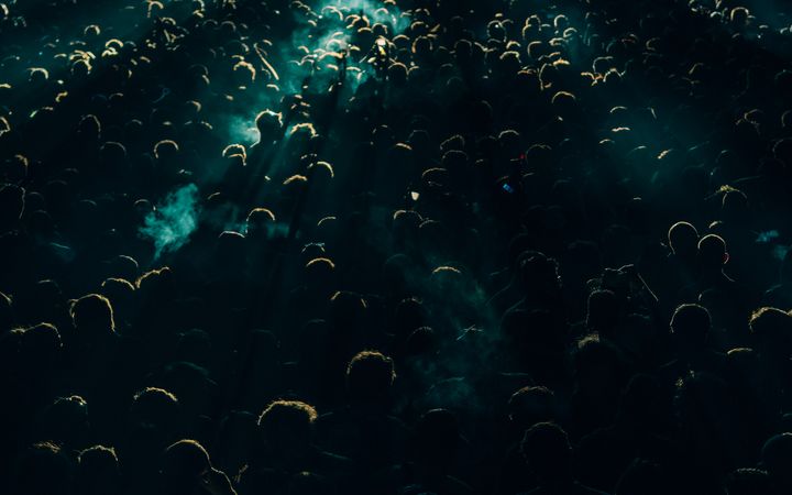 A lively concert crowd enjoying the music under bright spotlights at night, capturing the energetic atmosphere.