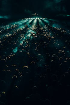 A lively concert crowd enjoying the music under bright spotlights at night, capturing the energetic atmosphere.
