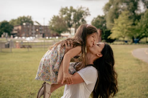A woman and her daughter are kissing each other