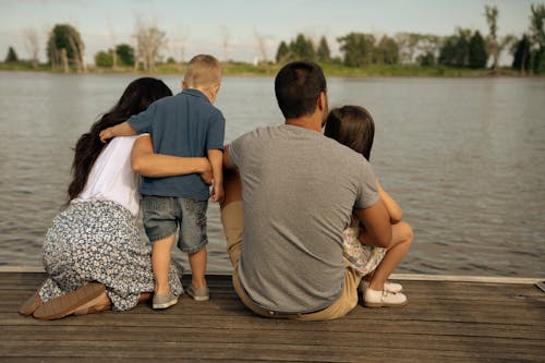 A family sitting on a dock by the water