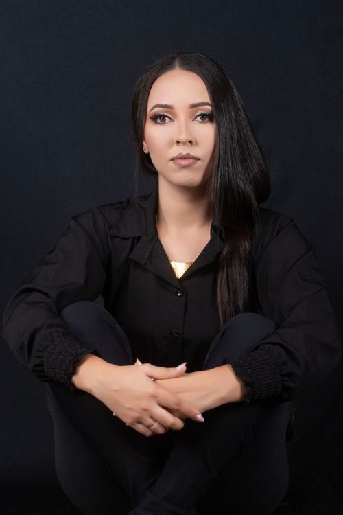 Free Elegant studio portrait of a woman in black clothing sitting against a dark background. Stock Photo