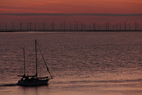 Free Sailboat Sailing Near Windmills during Golden Hour Stock Photo