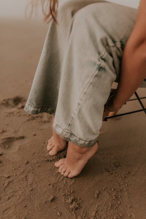Free A woman's feet are on the sand in a chair Stock Photo