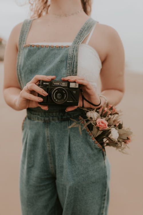 Free A woman holding a camera on the beach Stock Photo