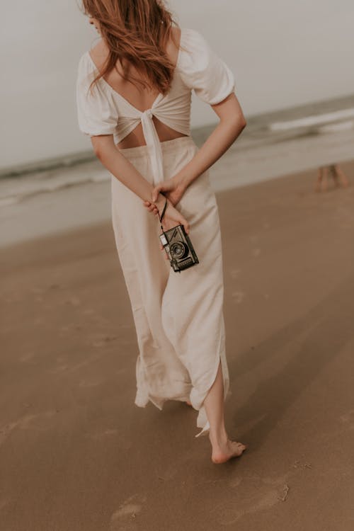 Free A woman in a white dress walking on the beach Stock Photo