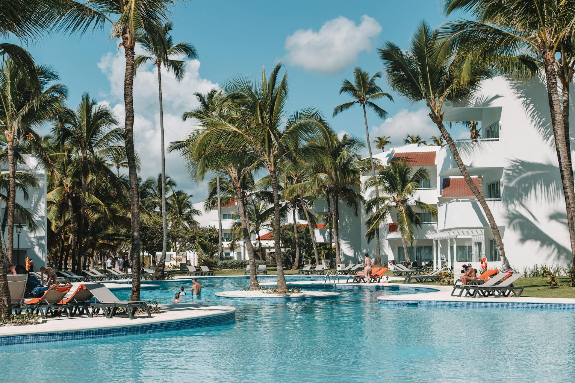 Charming resort pool surrounded by palm trees and villas in sunny Punta Cana, Dominican Republic.